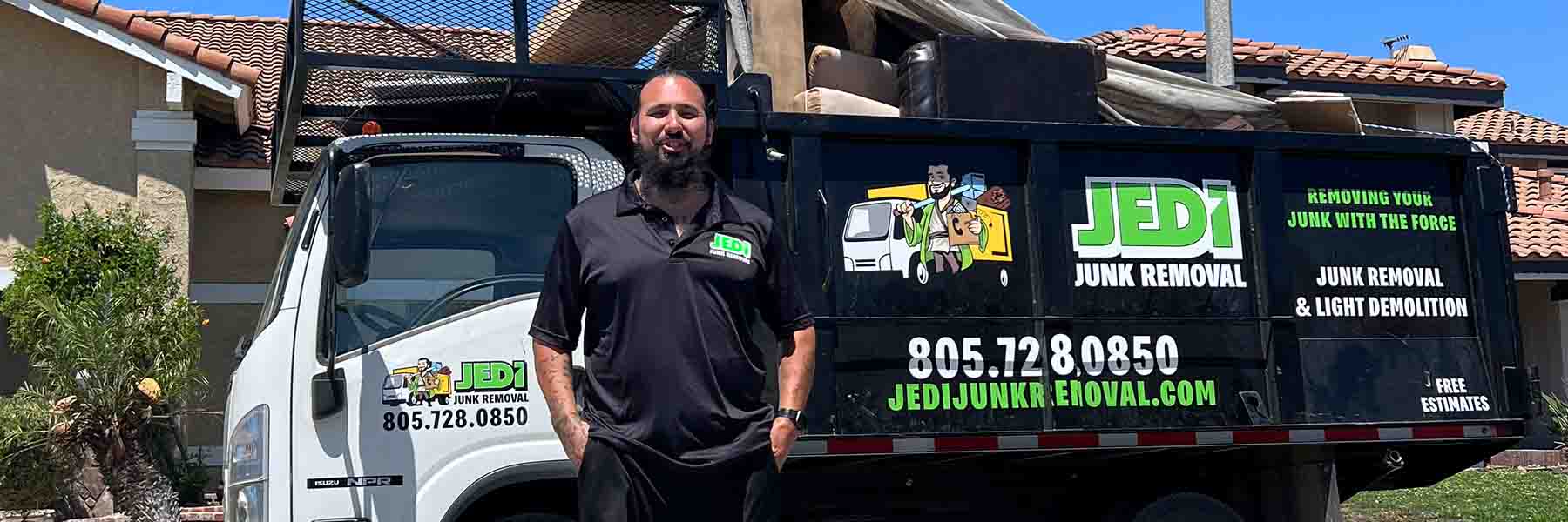 Junk removal owner standing in front of his fully loaded truck after a job