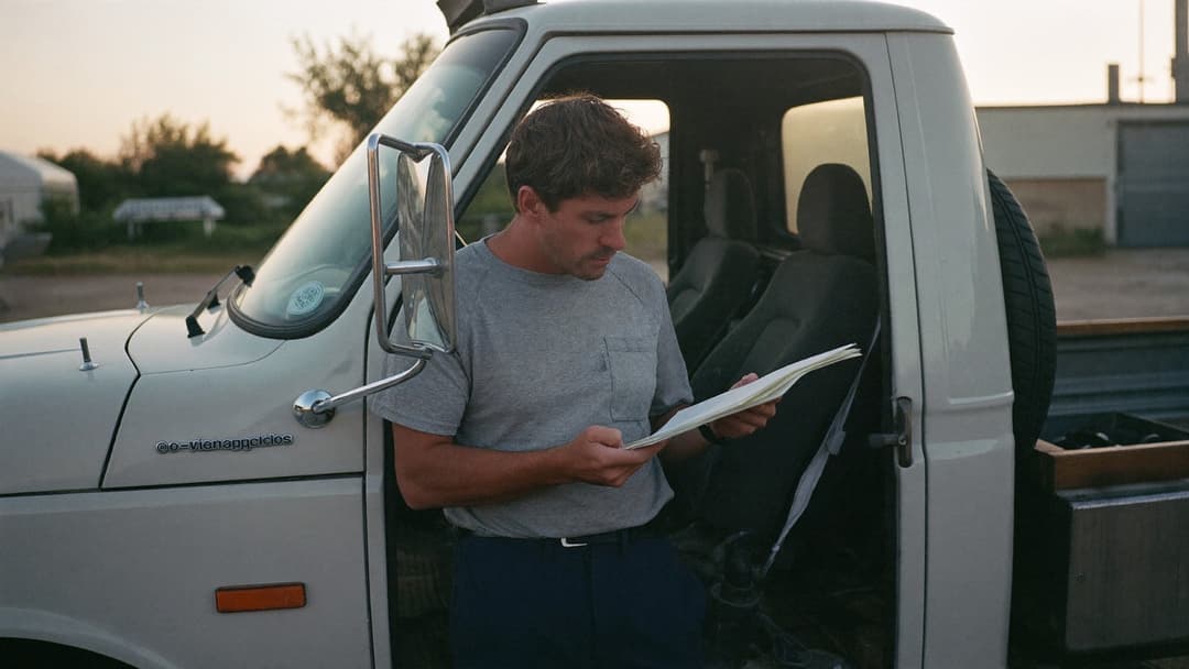 Junk removal owner at a kitchen table comparing bank statements and a laptop late at night