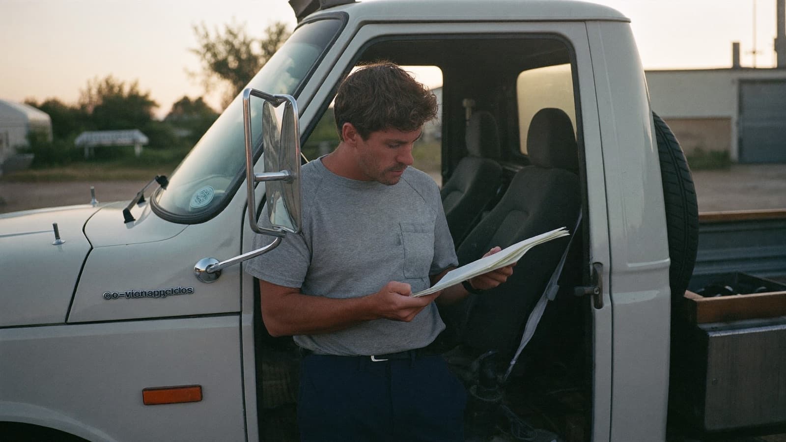 Junk removal owner at a kitchen table comparing bank statements and a laptop late at night