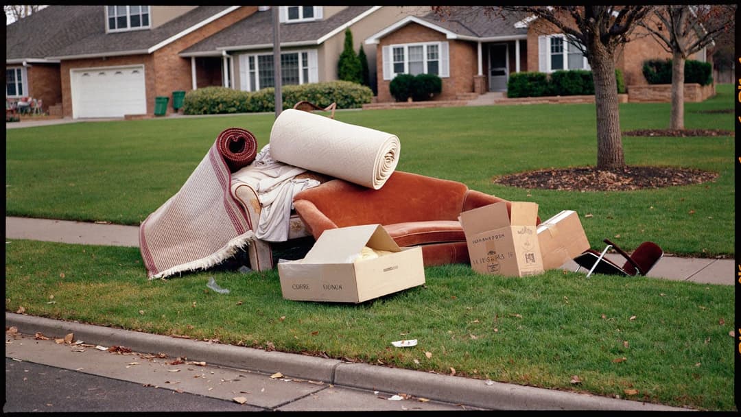 Junk removal crew loading furniture from a driveway into a box truck