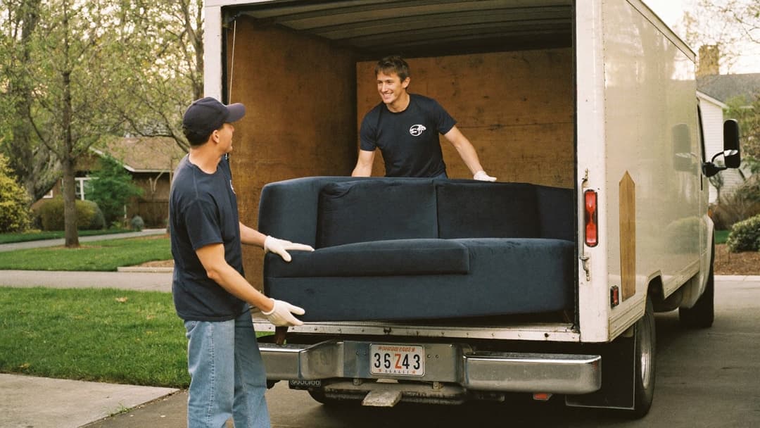 Junk removal founder loading a couch into a dump trailer at sunrise
