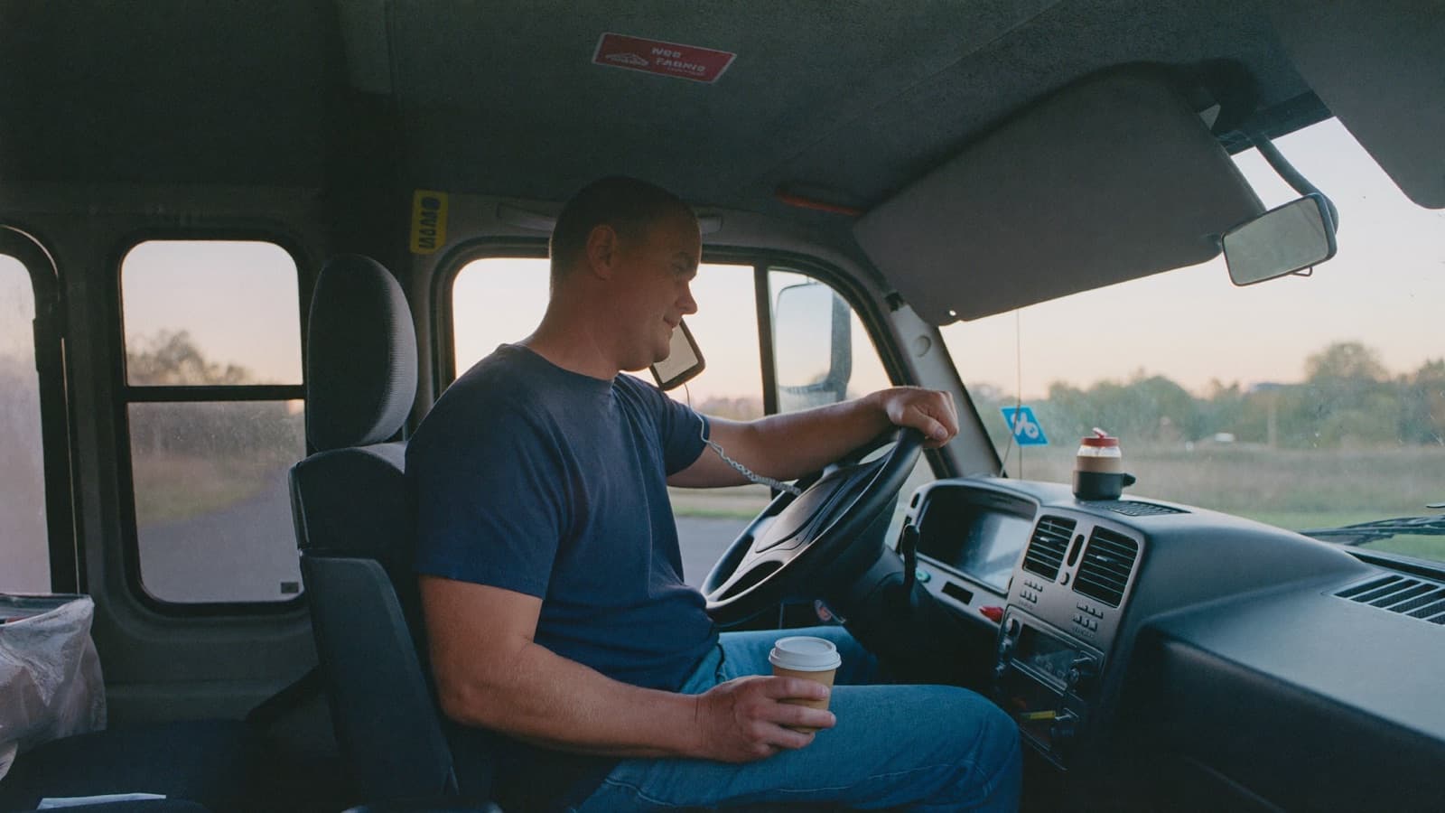 Phone ringing unanswered on a truck seat while a crew carries furniture in the background