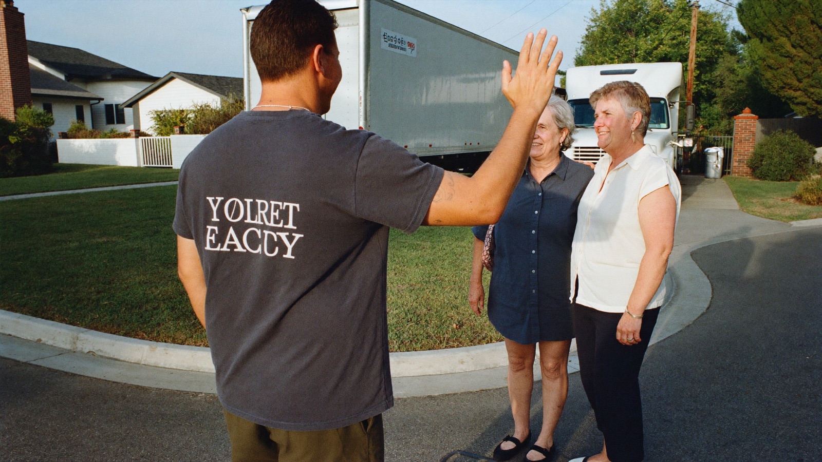Junk removal crew member shaking hands with a customer in a driveway after a job